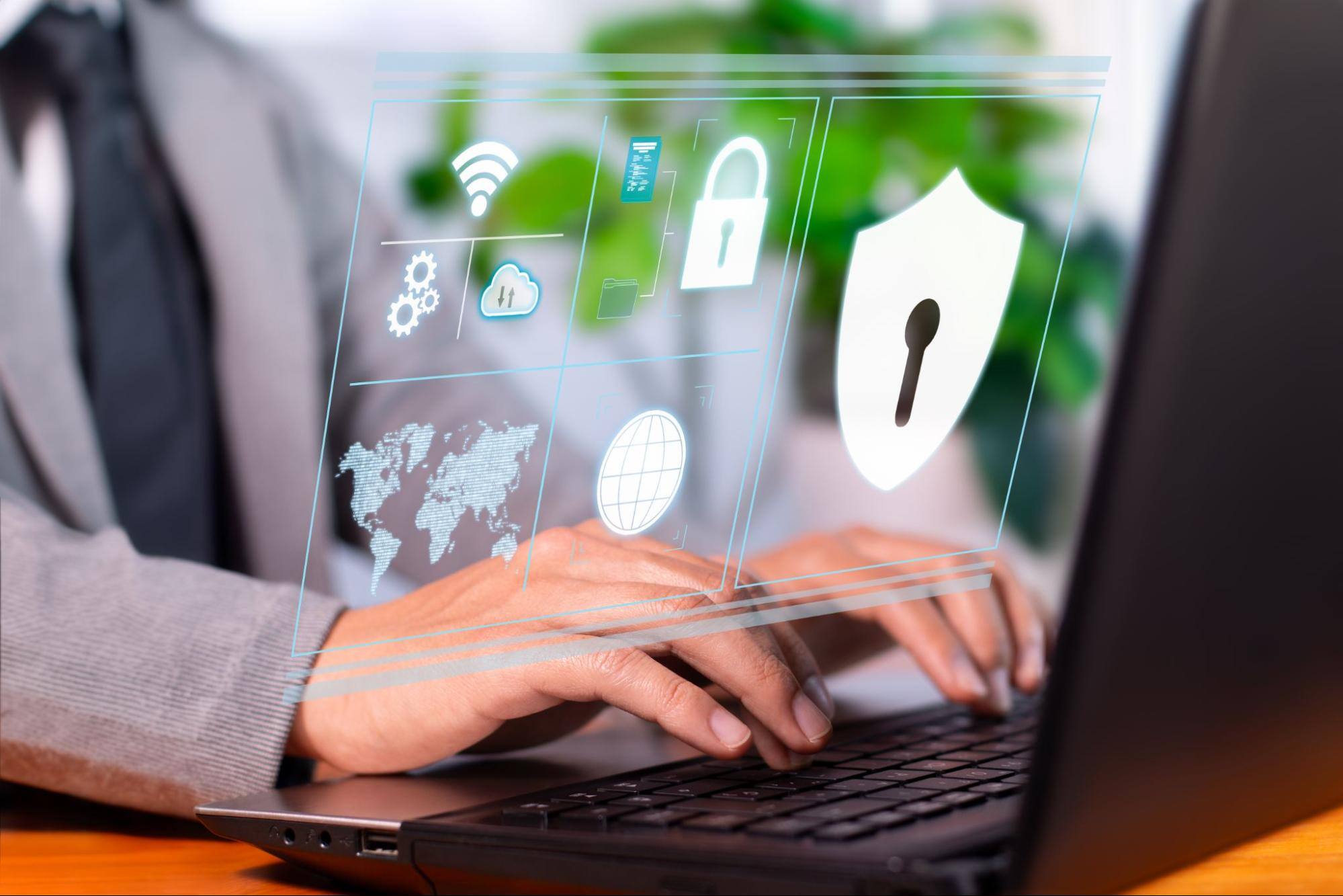 Man typing on a computer with security icons above the keyboard.