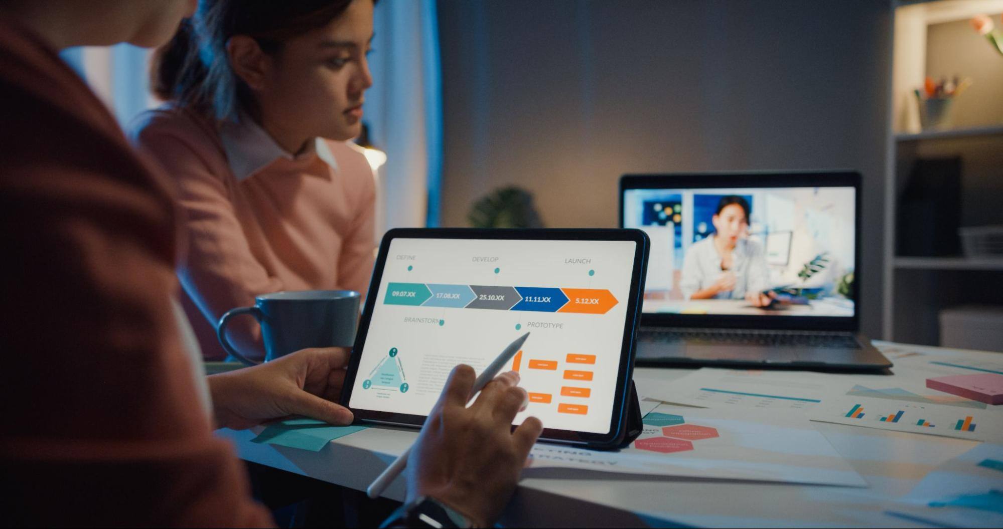 Two business professionals use two computers on a Zoom call.